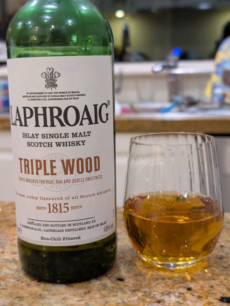 A bottle of Laphroaig Triple Wood, and a generous pour of Laphroaig Triple Wood in a glass 
