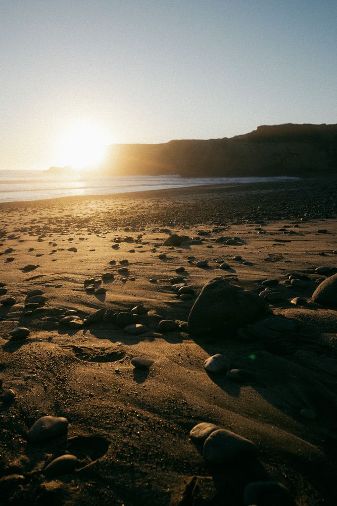 A photograph of a beach during golden hour with a view of the sun 