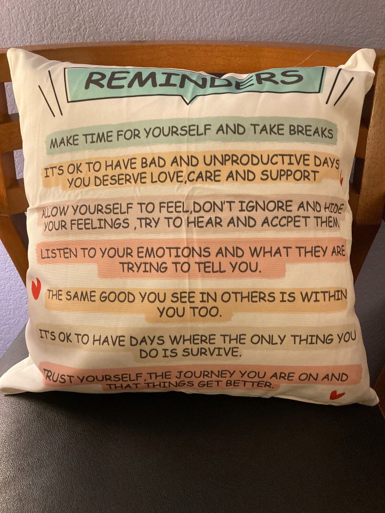 Square pillow that says - Reminders: Make time for yourself and take breaks. It's okay to have bad and unproductive days - you deserve love, care, and support. Allow yourself to feel, don't ignore and hide your feelings, try to hear and accept them. Listen to your emotions and what they are trying to tell you. The same good you see in others is within you too. It's okay to have days where the only thing you do is survive. Trust yourself, the journey you are on and that things get better.