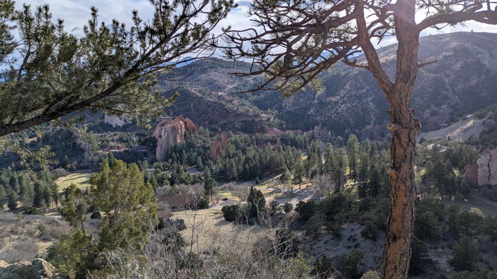 View from a hilltop in Colorado. Red rock formation and mountains. Lots of trees too. 