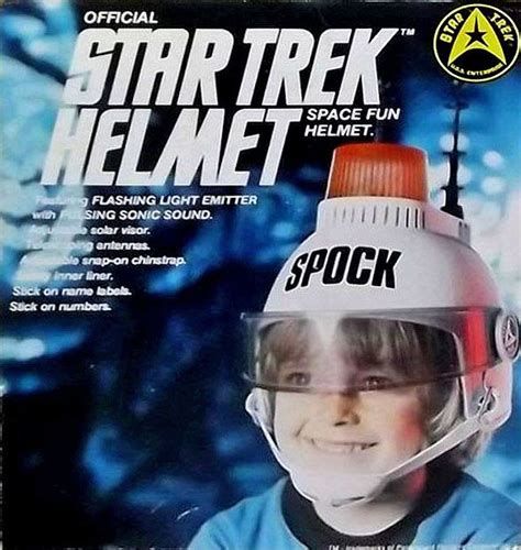 The front of a box for a toy called an "Official Star Trek Helmet (Space Fun Helmet.) featuring Flashing Light Emitter with Pulsing Sonic Sound."  Below this label is an image of a child wearing a white helmet with a chin strap and clear visor, topped with a large red alert light and black antenna, and labelled "SPOCK" in large block letters across the front.