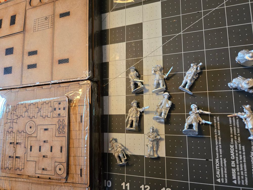 17th-century pewter minis and some MDF "Paris 1625" buildings wrapped in plastic