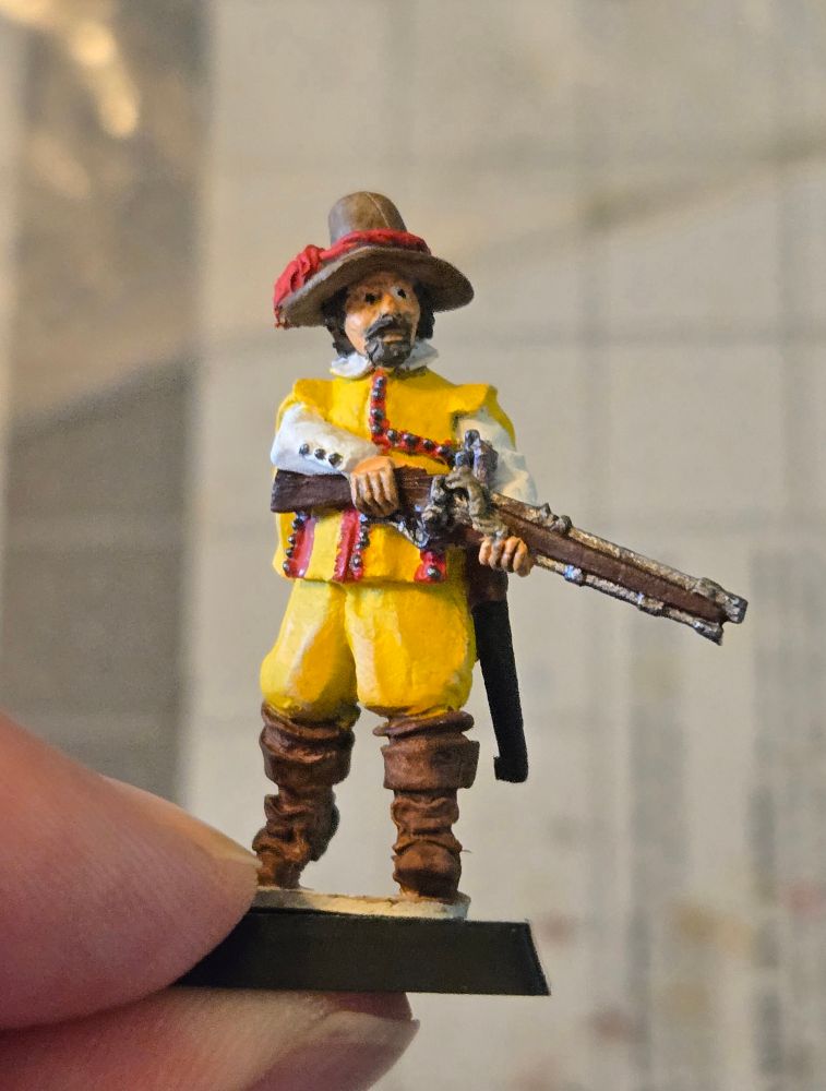 28mm Bloody Miniatures mini of a musketeer wearing a yellow and red tabard