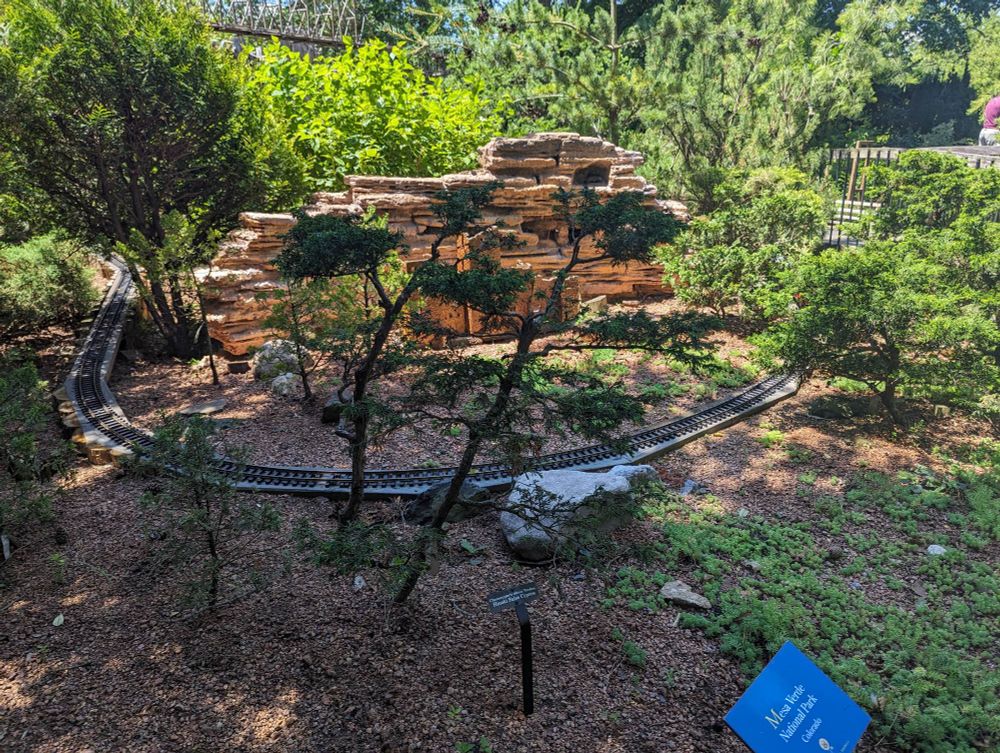 Miniature Mesa Verde National Park, with a model railroad track curving around rocky cliffs and miniature trees