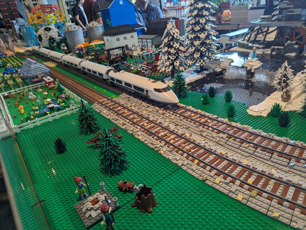 A huge Lego display with model trains running around the outside edge. This view shows parts of a winter forest and a farm; a large Lego soccer ball is visible towards the back.