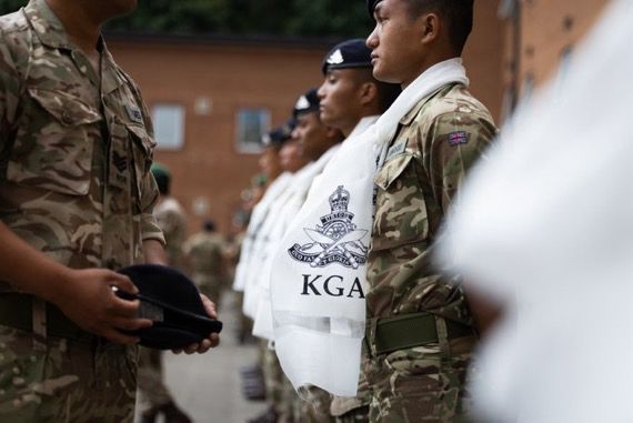 A British Army office is placing a new unit cap badge on a beret for presenting to a soldier.   