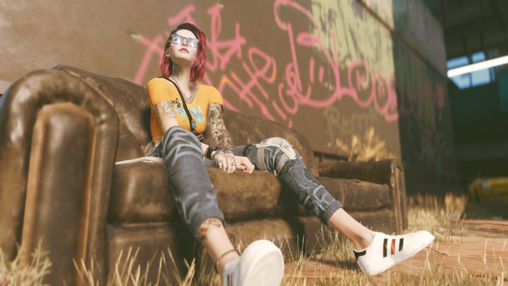 V sitting on a dirty old sofa sitting against the wall of a beat up apartment building with ample graffiti.
