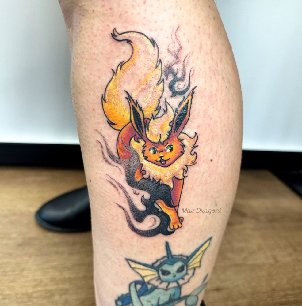 A tattoo of a flareon from Pokemon with swirly black stipple shaded flames to the left and top right of the Pokemon 
