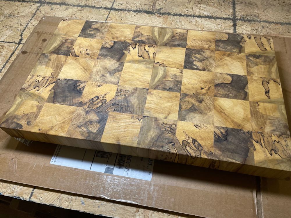 Cutting board sitting on cardboard as I treated it with mineral oil. Square blocks of end grain poplar with color and figure from spalting.