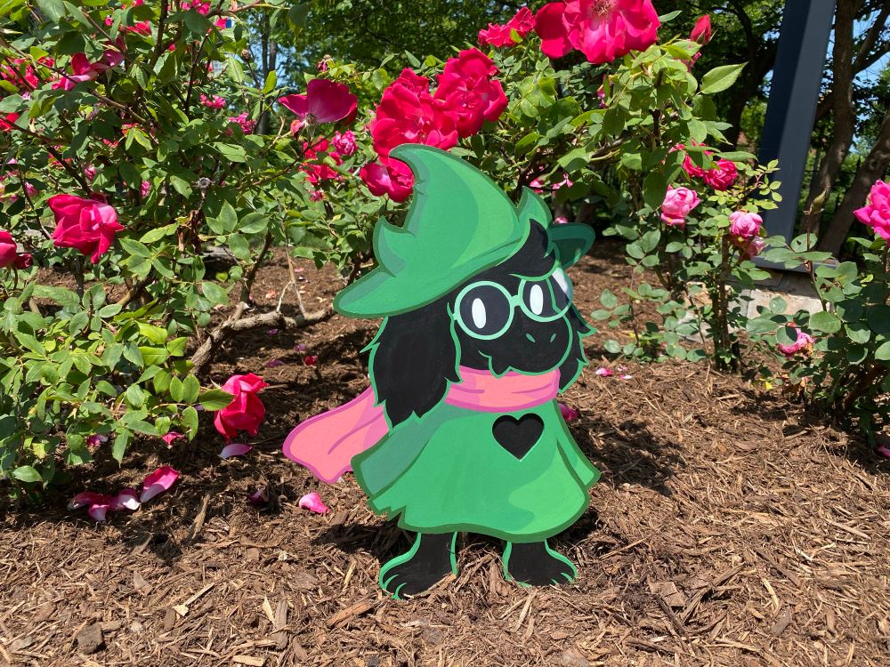 Wood ralsei next to a wild rose bush 