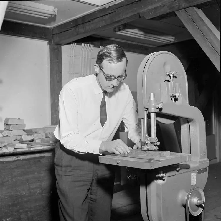 Van der Grinten bezig met een lintzaag.