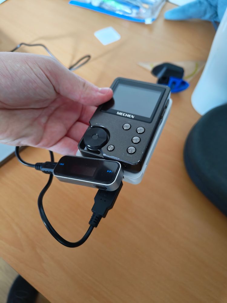 An FM transmitter plugged into a DAP, the FM transmitter is being charged by a MagSafe powerbank over USB 