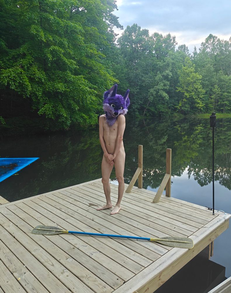 Standing on the dock of a lake, nude