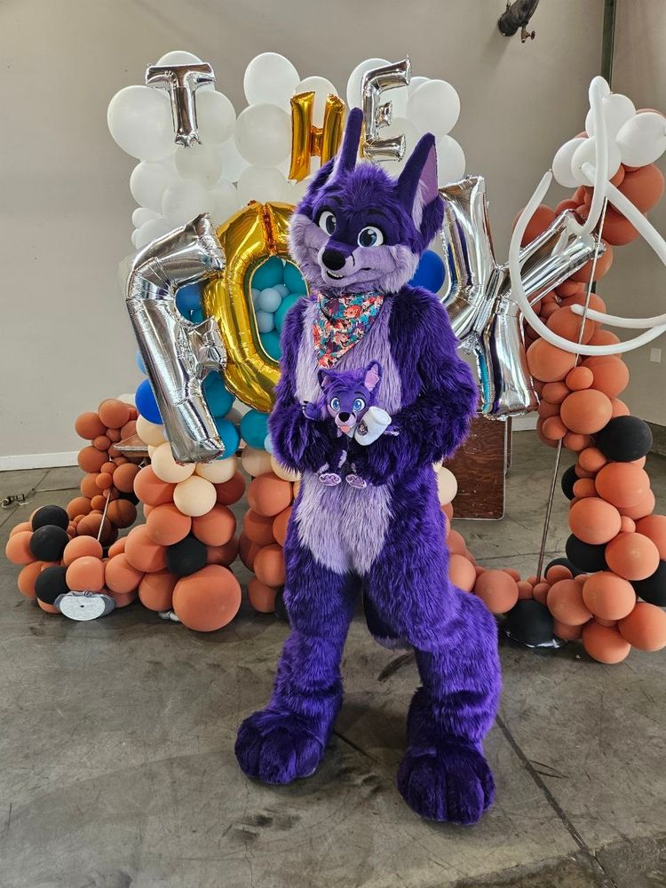 Fullsuiting, while holding Little Niq, behind a Fox sign
