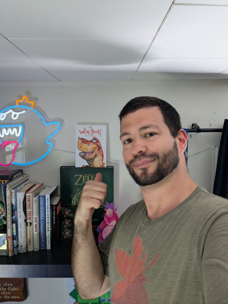 Me in my room, standing on the bed in front of my stream backdrop shelf, pointing at my sealed DVD copy of 