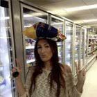 imagem do meme "OMG SHE'S SO CRAZZZZZZY LOVE HER", em que consta uma mulher em um mercadinho fazendo sinal de paz com ambas as mãos enquanto equilibra na cabeça um pacote do que parece ser 2kg de batata frita e faz biquinho pra câmera