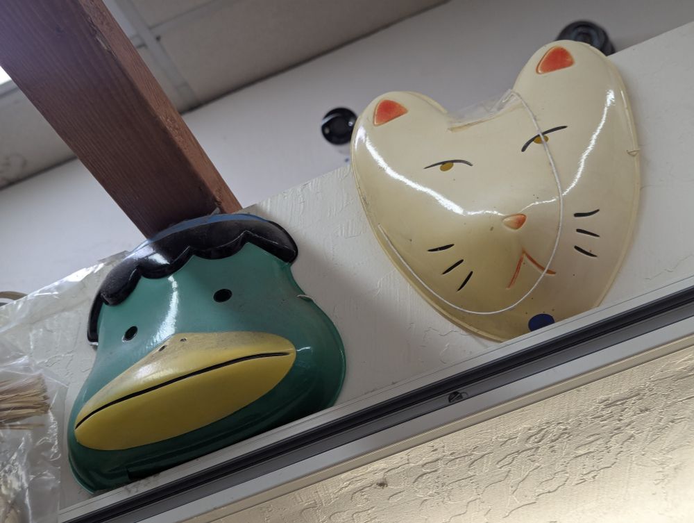 Plastic masks of a kappa and kitsune. The kitsune looks amusingly unimpressed, or maybe even annoyed.
