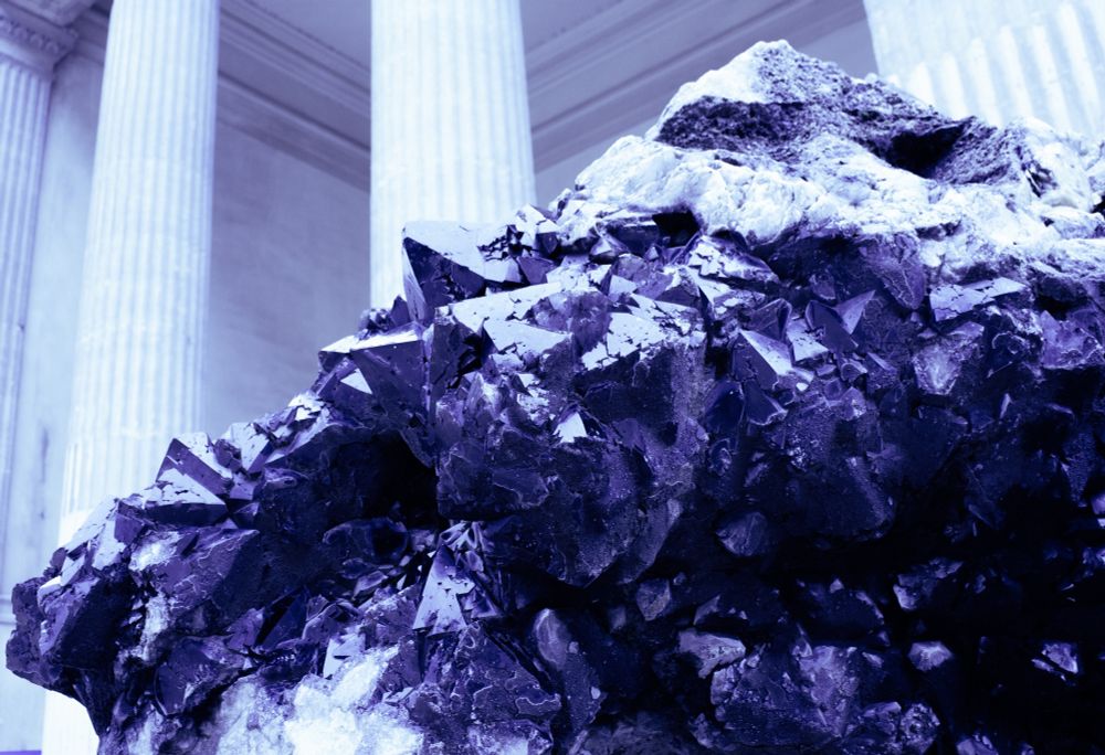 Photo au jardin des plantes, très grosse roche au premier plan et des colonnes qui jaillissent derrière.