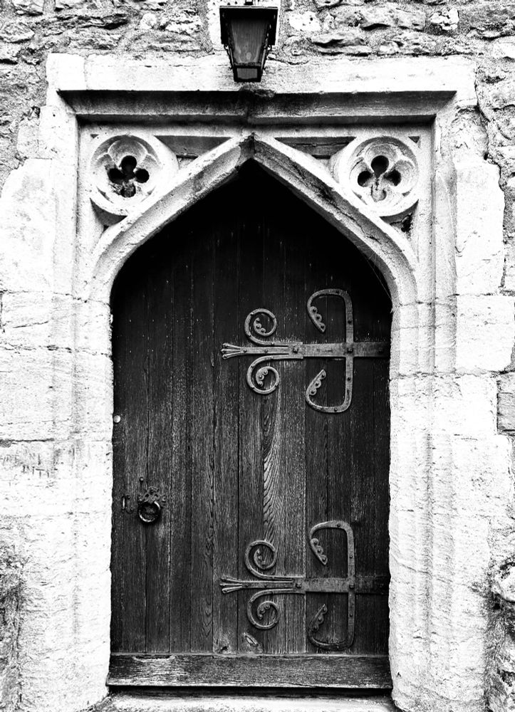 Large oak church doorway with faint inscribed writing scratched into stone bordering the door