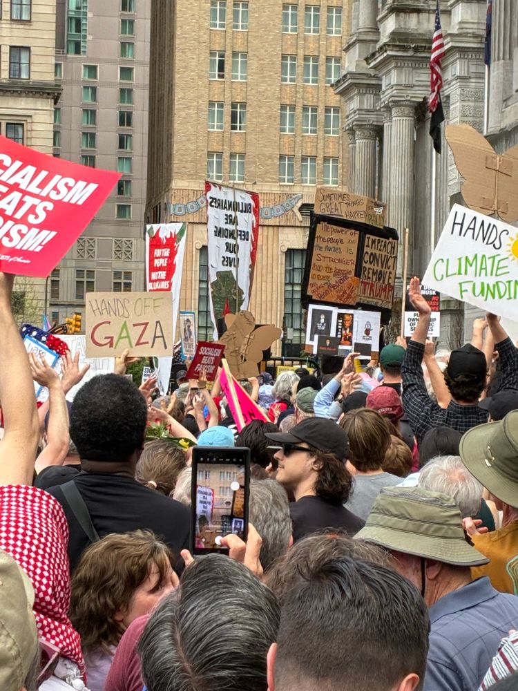 A group of people protesting in Philly. One sign says Hands Off Gaza and another says Hands Off Climate Funding. 