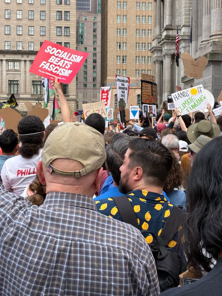 A group of people protesting in Philly. Signs say Socialism Beats Fascism, Hands Off Climate Funding, and Hands Off Gaza