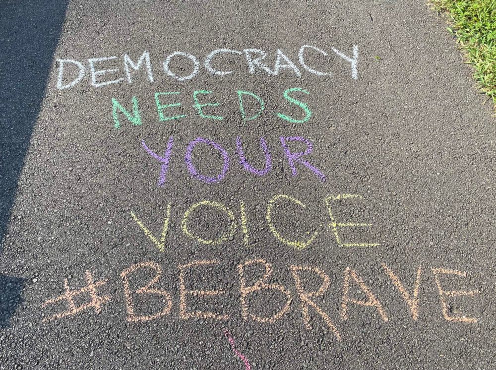 Sidewalk chalk message: Democracy needs your voice #bebrave