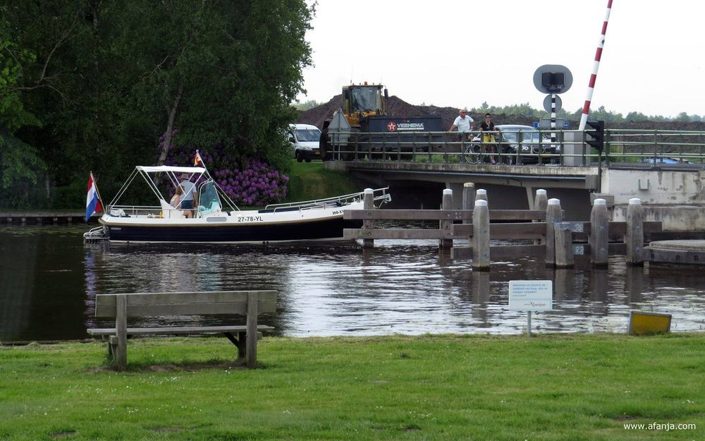 een bootje passeert een brug