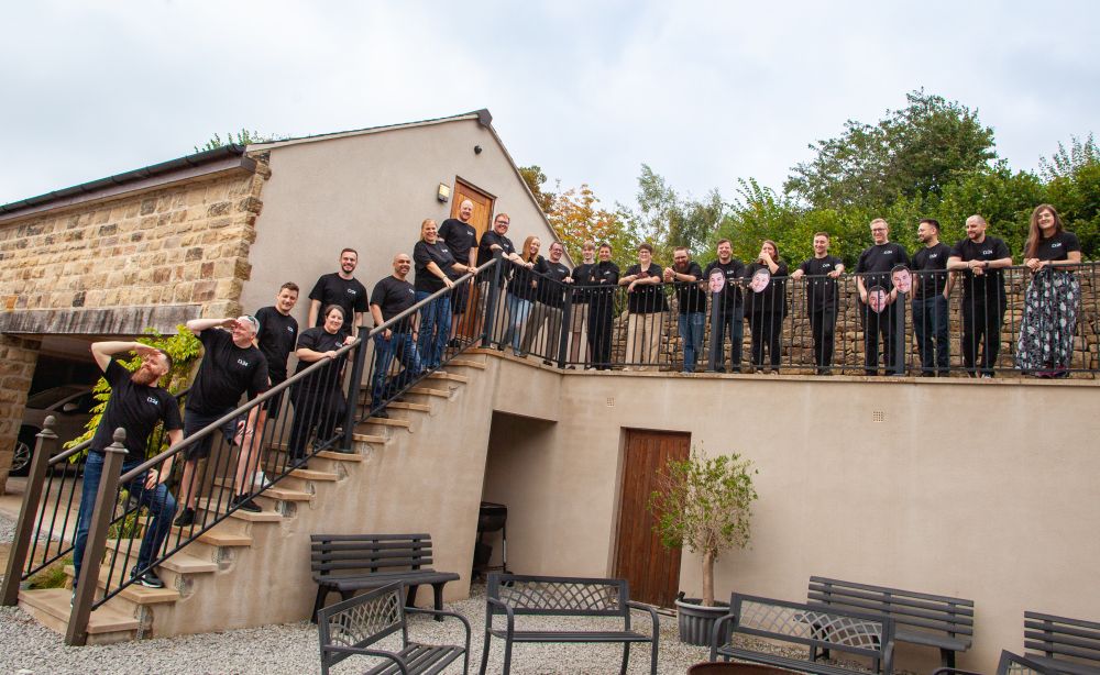 Group shot of CODECABIN24 attendees, lining the stairs, laughing, all wearing black CODECABIN branded t-shirts