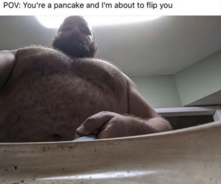 POV shot from a frying pan of a large hairy man about to flip a pancake 