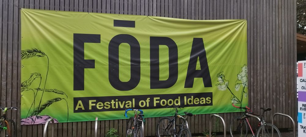 Cartaz em parede de madeira, na cor verde, dizendo:
FODA
A Festival of Food Ideas 
