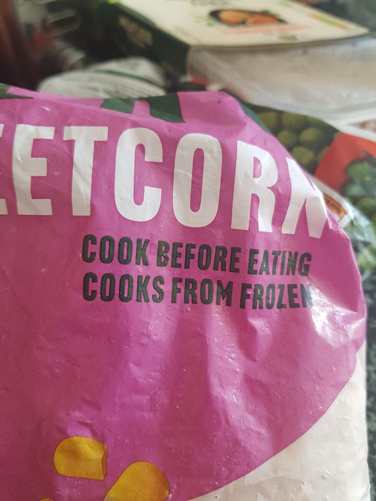 A bag of frozen sweetcorn with the instruction.  COOK BEFORE EATING.
