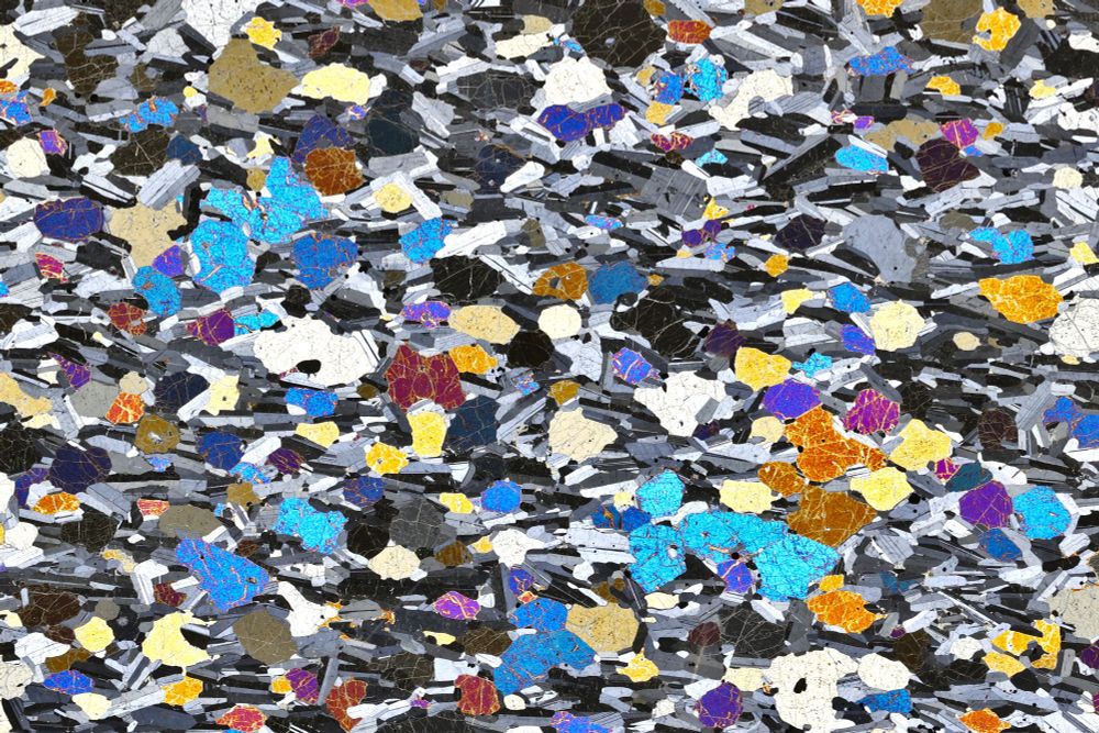 Just one of the best thin section images you're likely to see. Brightly coloured fresh olivines in blues, yellows, and oranges among smaller black, white and grey plagioclases, which generally define a fabric from left to right.