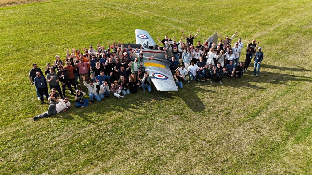 Flightradar24 crew members posing for a photo at an airfield surrounding a Chipmunk aircraft.