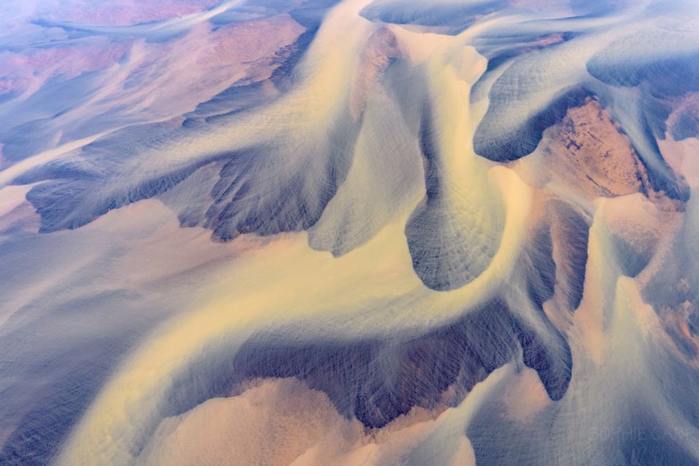 Weird orange, grey and yellow river braids seen from a drone. Lots of swirly patterns of the meandering braids and channels.