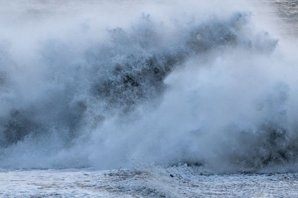 A huge crashing wave giving up white spray.