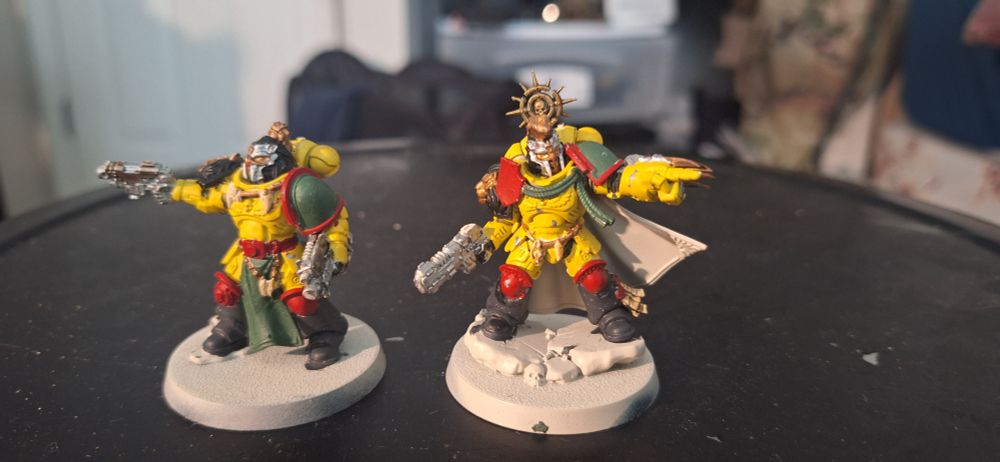 Two space marine minis with yellow bodies, red knees, and black boots