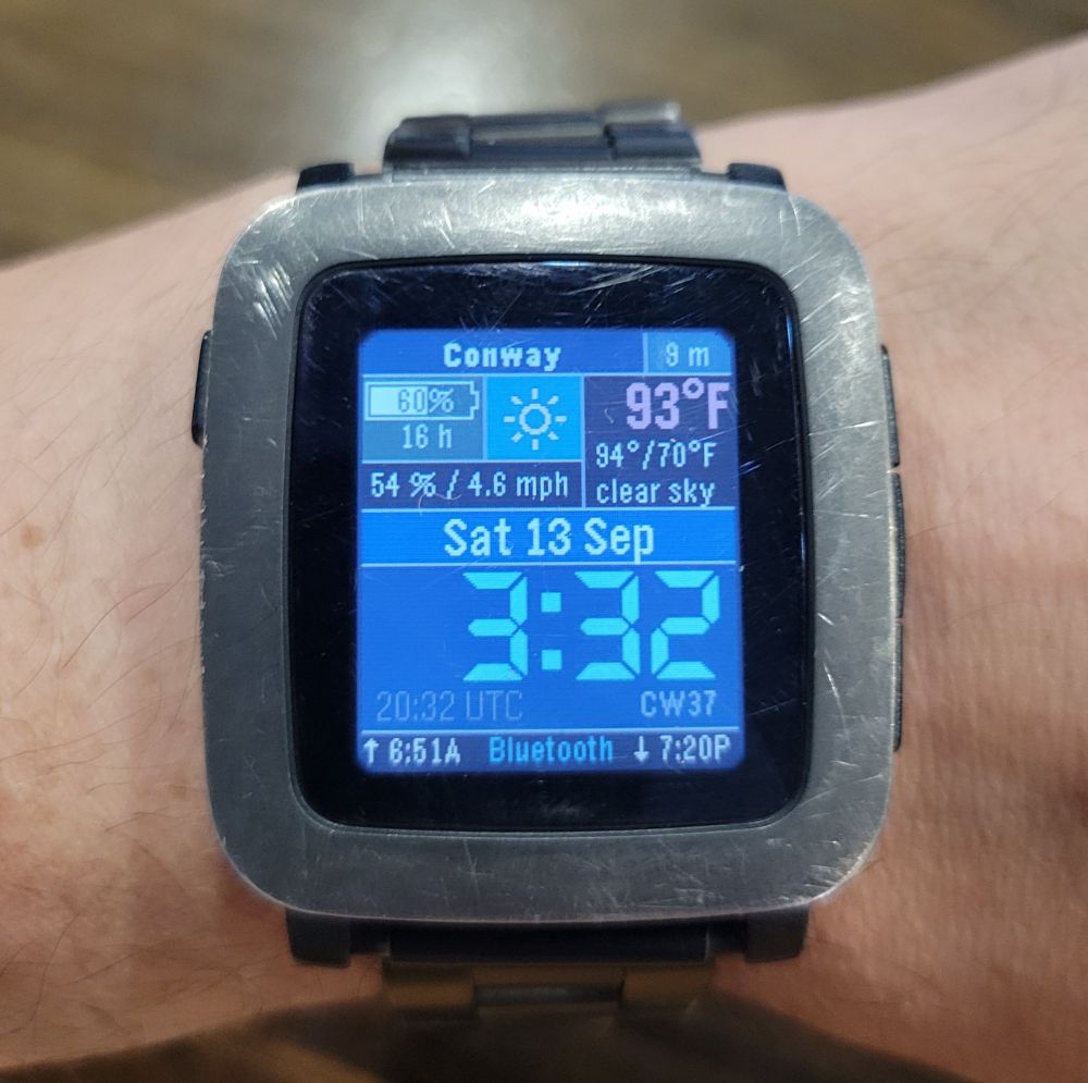 A scratched and worn Pebble Time watch with the backlight on, showing the Multifunction 7 Segment watch face, on some white guy's wrist.