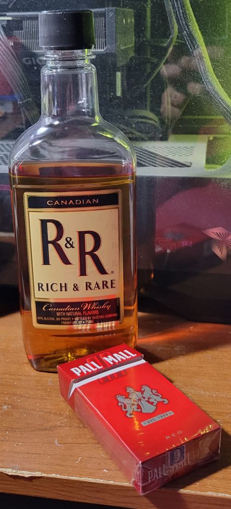 A partially-drunk bottle of cheap R&R whiskey and an open pack of Pall Mall red cigarettes