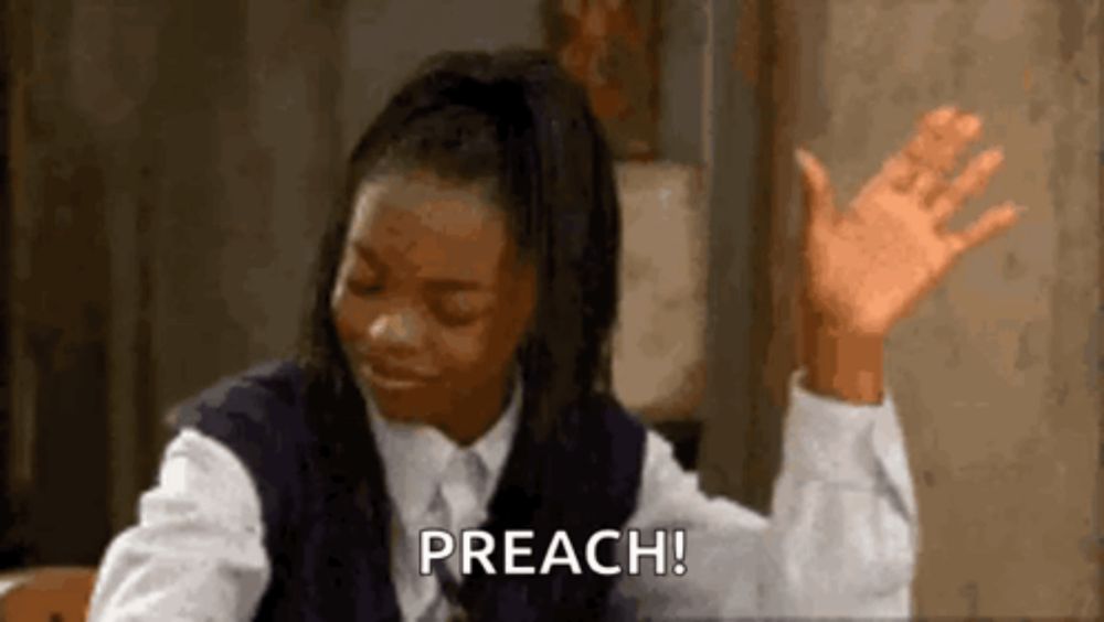 a woman in a school uniform is sitting at a table with her hands in the air and saying preach .