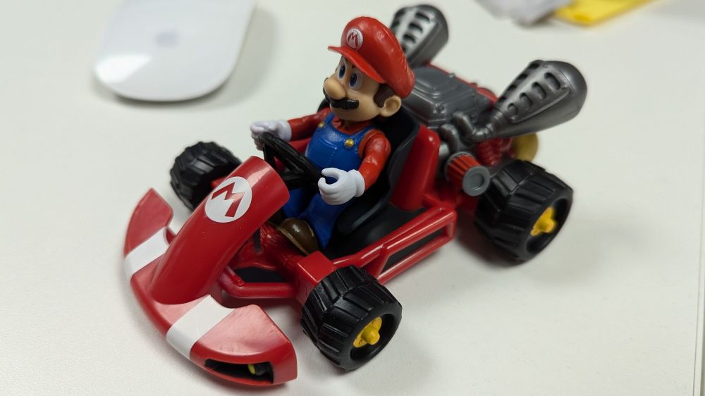 Toy Mario in a Mario Kart Kart invoking rizz.