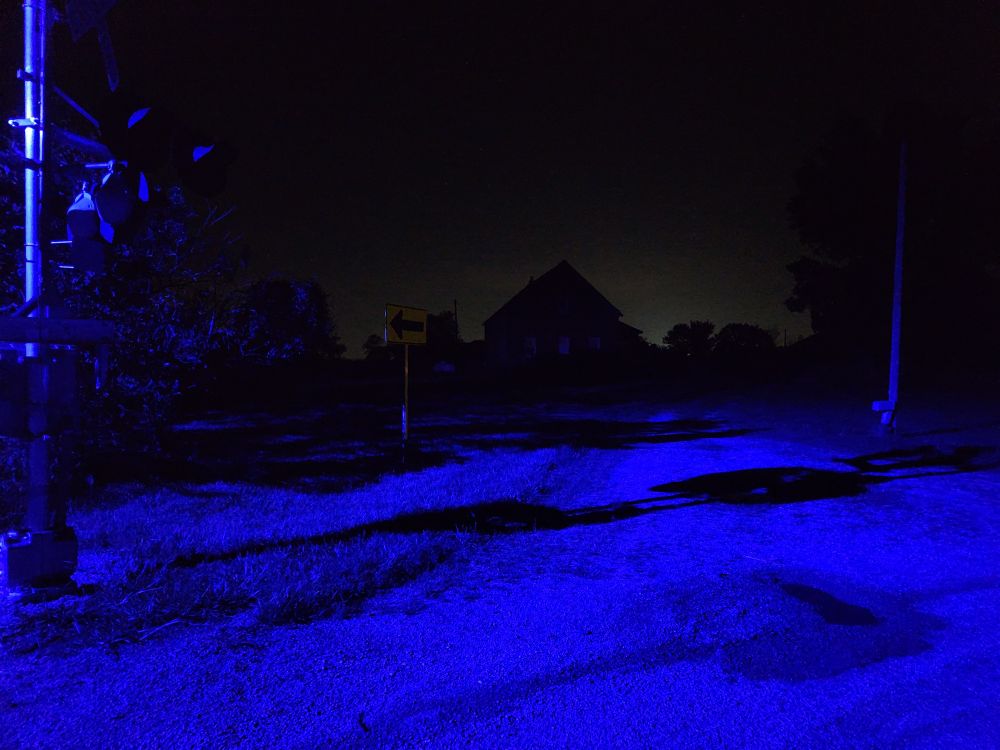Another shot of the previous railroad, this time pointed at a building in the distance. The building is backlit by distant artificial lighting.