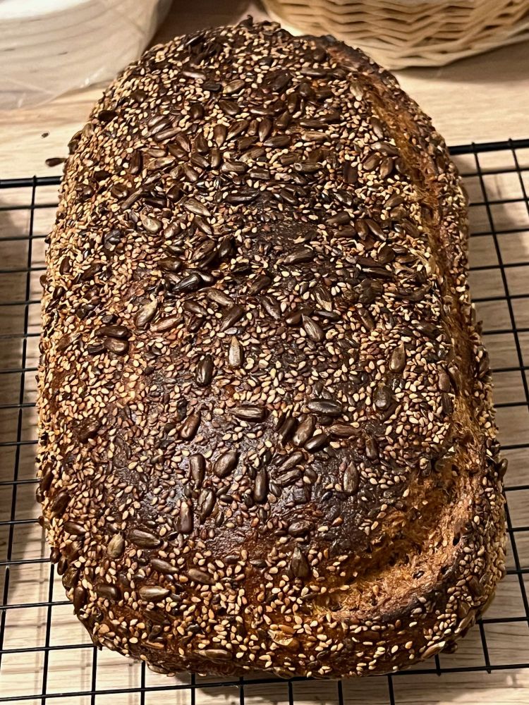 A second homemade baked loaf of bread covered in seeds.
