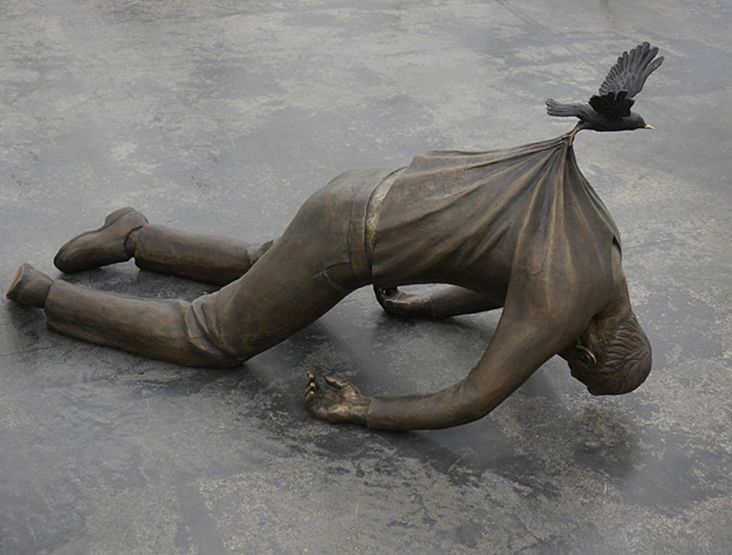 Statue of broken man being lifted by bird 