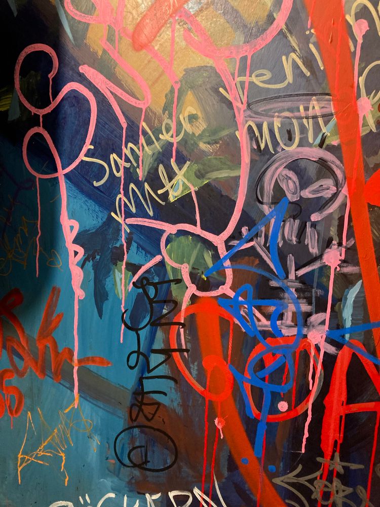 Graffiti and scribbles on a toilet wall. Beautiful colours, pink, red, blue, turquoise, yellow, green.