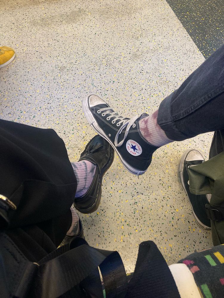 Two people sitting beside each other on the overground, with matching pink socks 