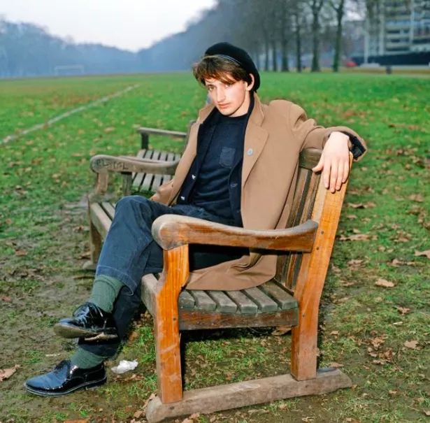Pat Nevin dressed to impress on a park bench by a football pitch, 1985. 