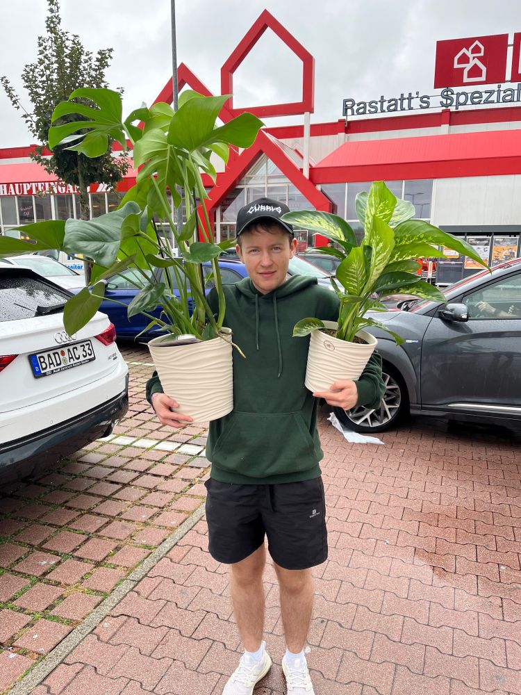 foto von mir auf dem bauhaus parkplatz mit zwei zimmerpflanzen im arm