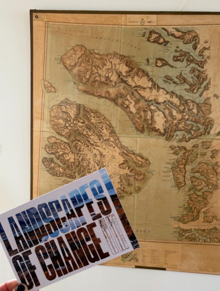 a map of the Arctic with a card held in front that reads 'landscapes of change' in bold black lettering.