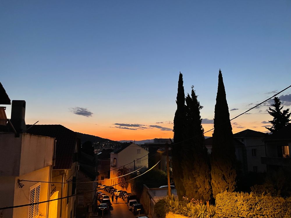 Sunset - Split. The sun is hidden behind the hills but shades of red and orange and pink remain as the sky darkens