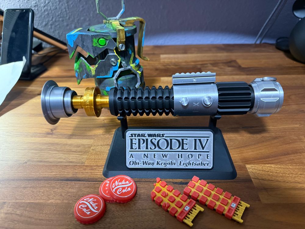 Various 3d printed toys: Star Wars lightsaber replica, Terminator CPU chips (damaged & pristine), Nuka Cola bottle caps, Chompers from Arcane.
